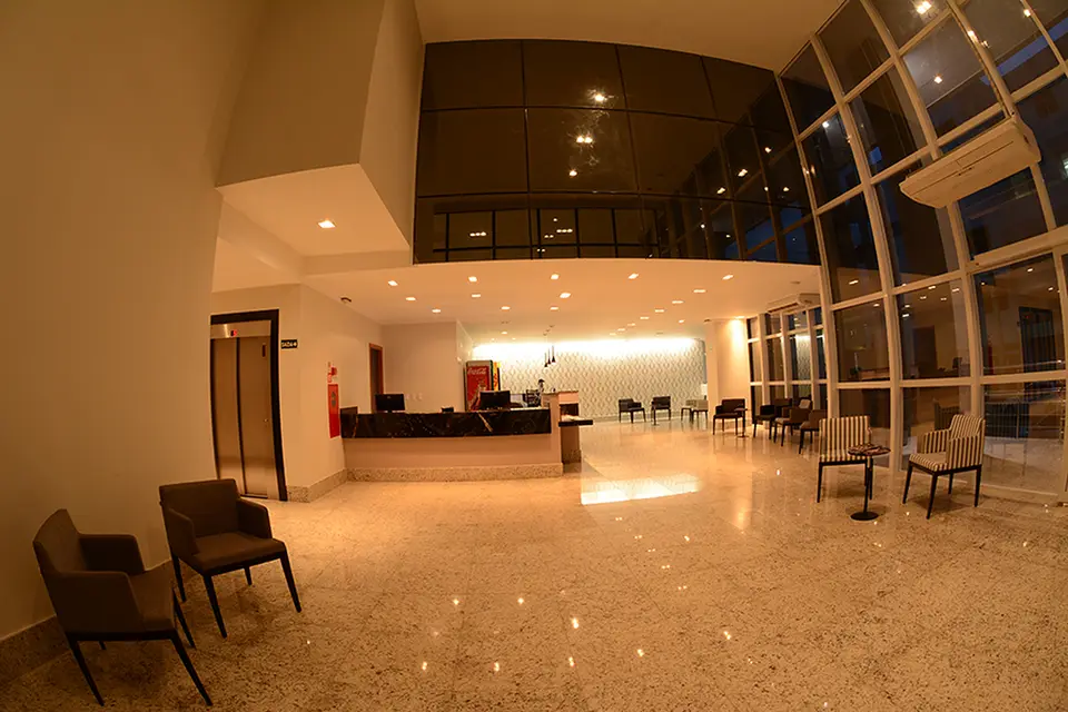 Recepção e lobby do Agil Hotel com pé-direito alto e vidraça